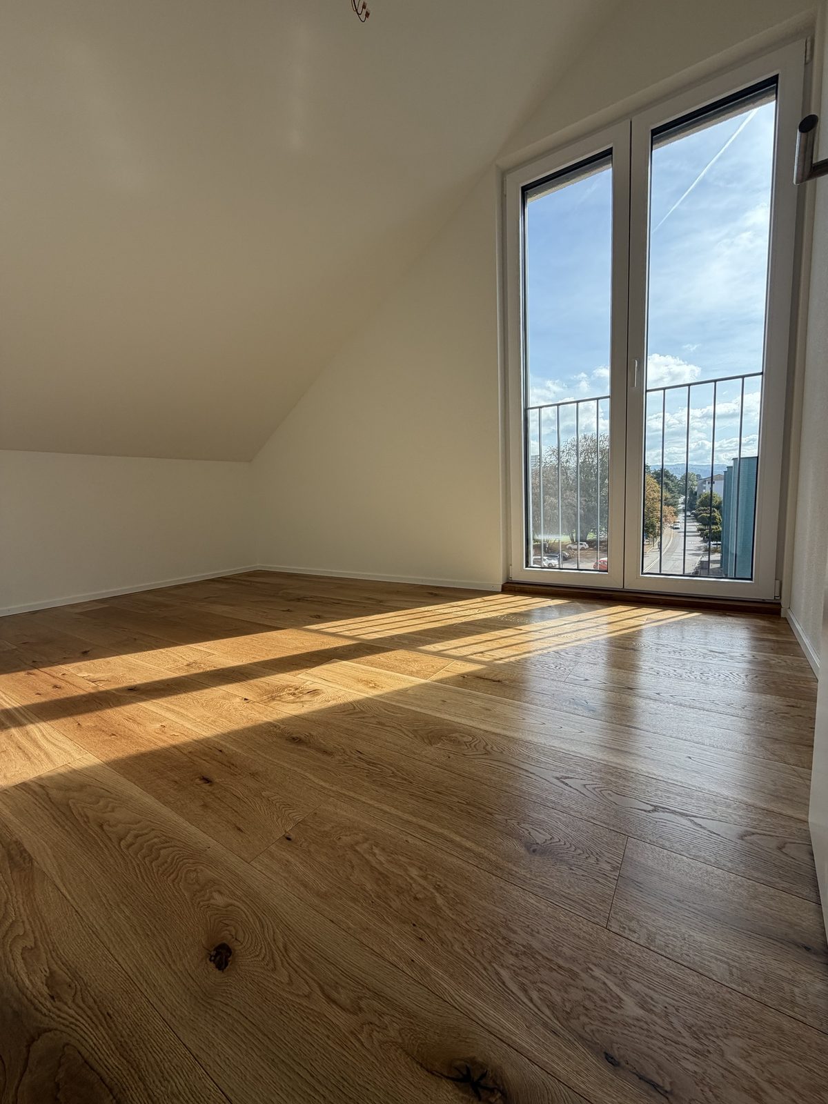 Dachzimmer mit Balkontüre und geölter Eiche im Streiflicht